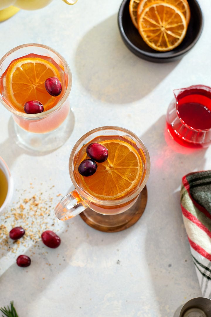 A cranberry hot toddy in a glass mug.