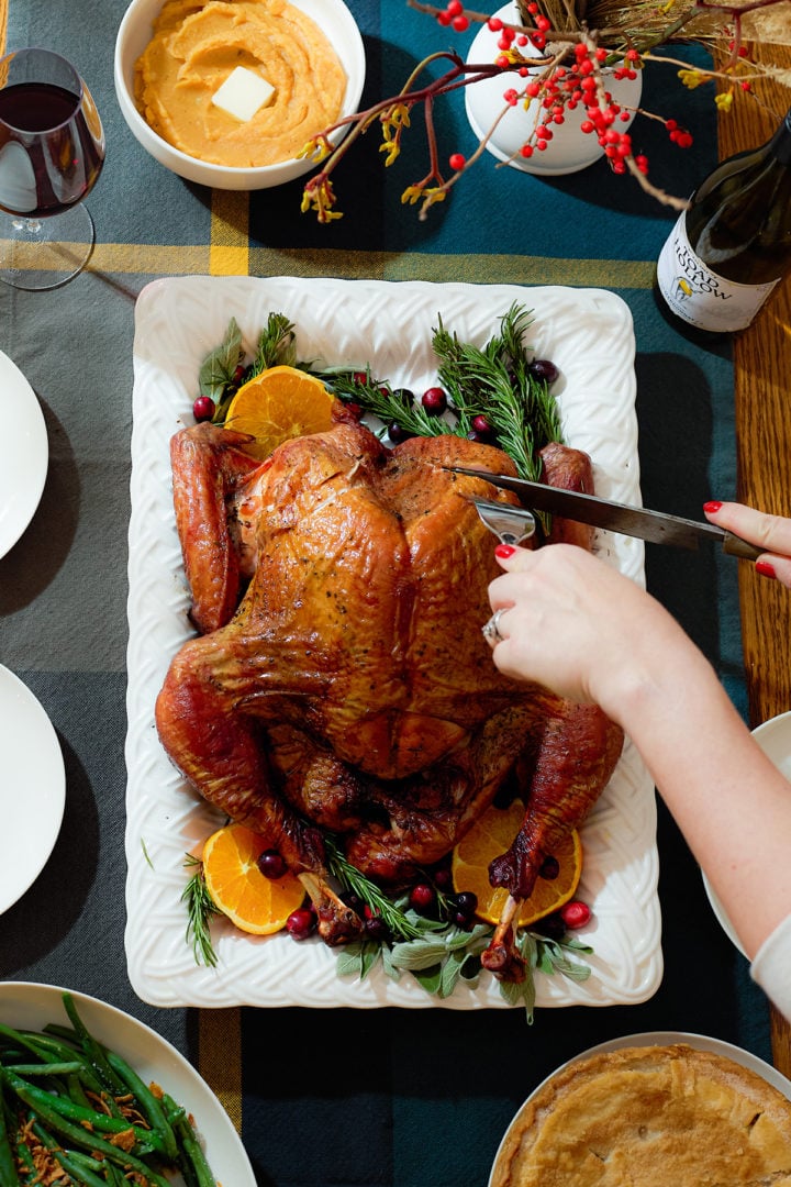 Carving a spatchcock smoked turkey on a serving platter.