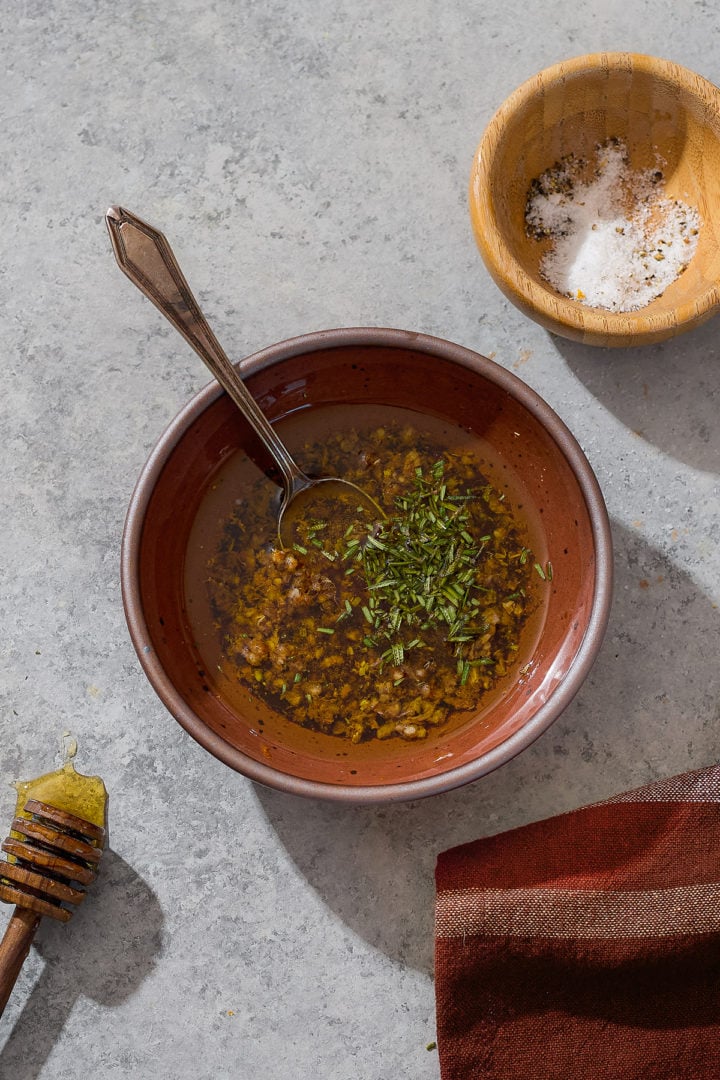 Bowl of honey, olive oil, garlic, rosemary, and orange zest mixed together for roasting parsnips and carrots.