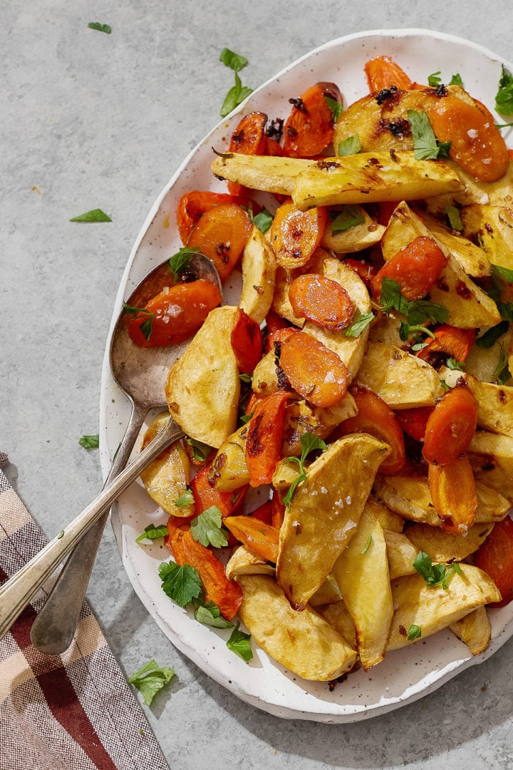 Platter of roasted parsnips and carrots tossed with honey and fresh herbs, ready to serve.