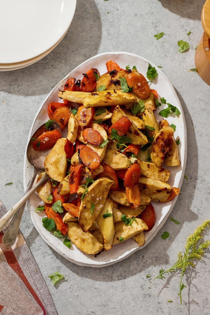 Serving platter of honey roasted parsnips and carrots on a table, ready for a holiday meal.