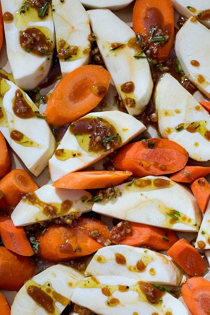 Sliced parsnips and carrots coated with a honey, garlic, and rosemary mixture before going into the oven.