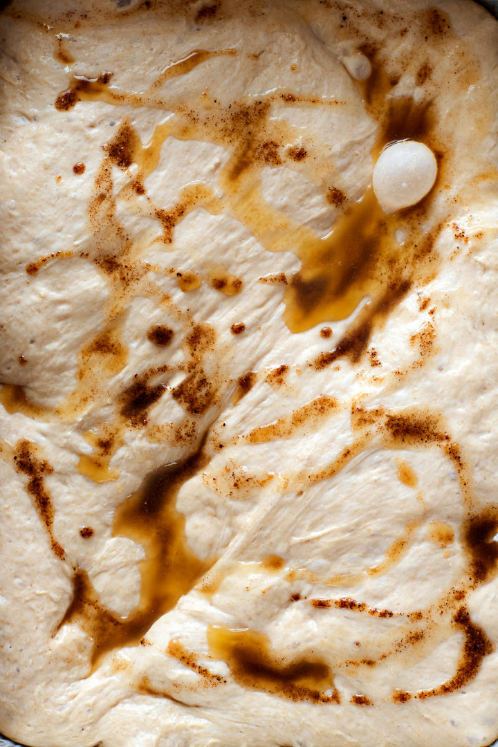 Close-up of the same focaccia dough after browned butter has been drizzled over the surface in streaks.